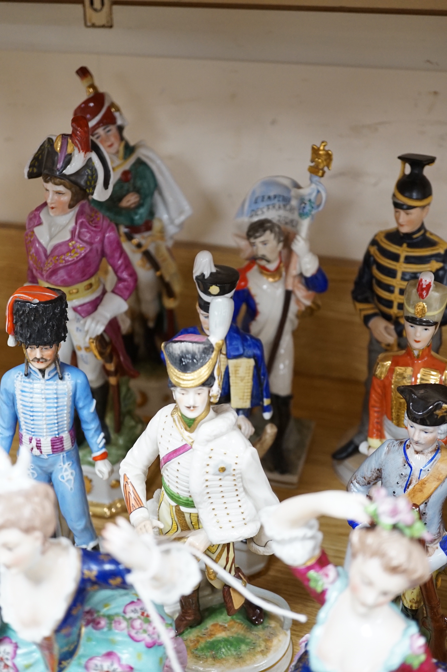 A group of Continental porcelain military figures, two porcelain figures of dancing females and four pieces of tableware in the form of fruit